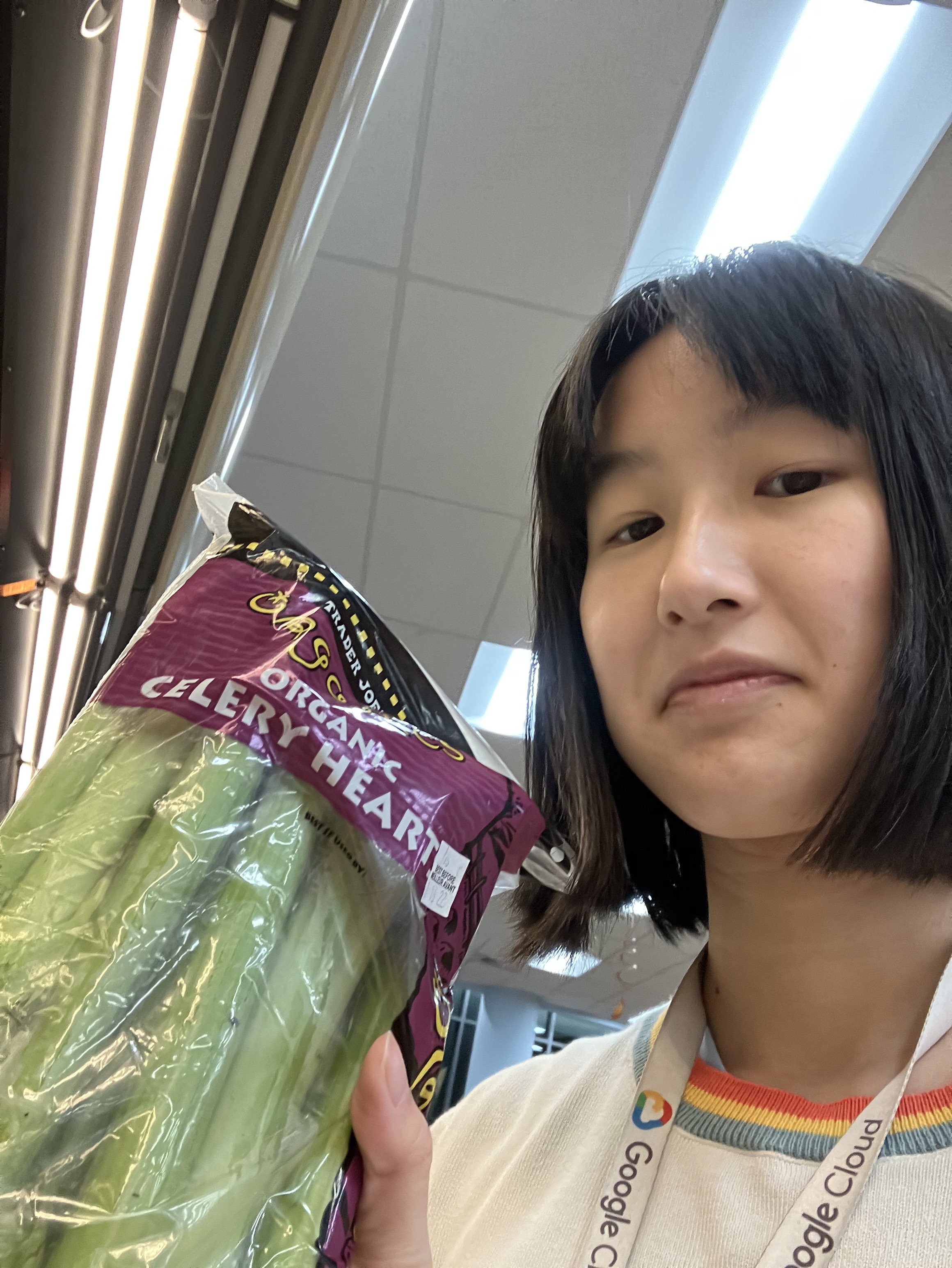 Dani holds celery with a disgruntled look on their face